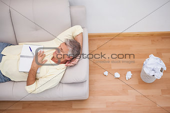 Man lying on couch with crumpled papers