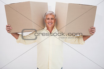 Smiling man balancing heavy cardboard boxes