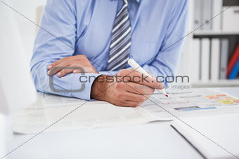 Businessman marking the newspaper with marker