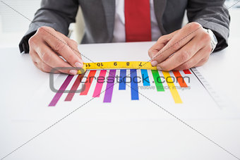 Businessman measuring graph with tape