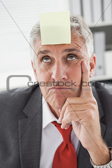 Confused businessman with sticky note on head
