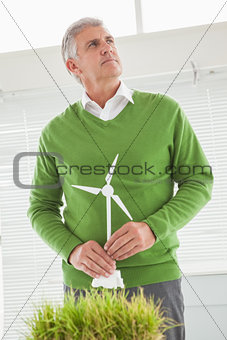 Casual businessman holding model wind turbine