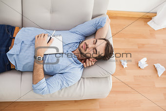 Casual man lying on couch with crumpled papers