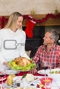 Woman serving roast turkey to her husband