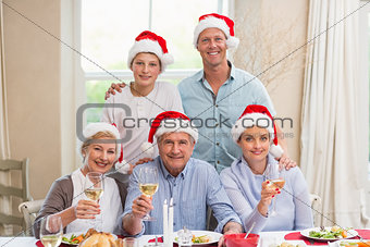 Happy extended family in santa hat toasting at camera