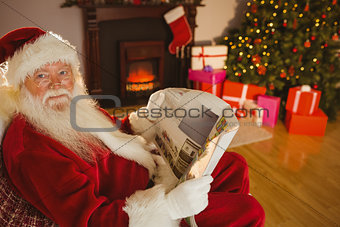 Smiling santa claus reading newspaper