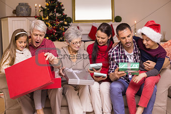 Multi generation family opening gifts on sofa