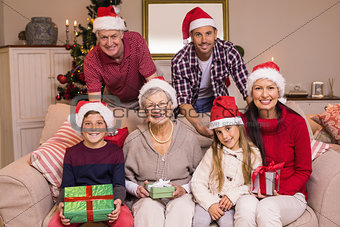Portrait of a happy extended family in santa hat holding gifts