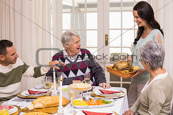 Woman holding turkey roast with family at christmas
