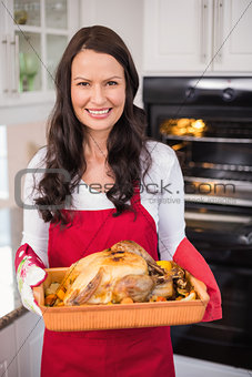 Happy brunette holding her roast turkey