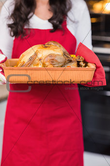 Mid section of woman holding roast turkey