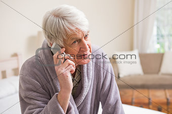 Senior man making a phone call on bed