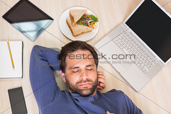 Sleeping man lying on floor surrounded by his things