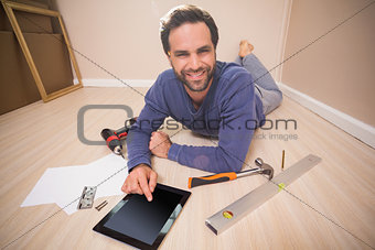 Casual man lying on floor using tablet pc for DIY instructions