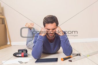 Casual man lying on floor using tablet pc for DIY instructions