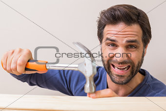 Casual man hammering his finger by accident