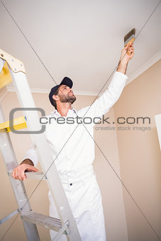 Painter standing on ladder painting roof