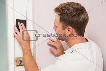 Man hand sanding the door before refinishing
