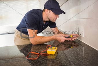 Electrician unscrewing face plate of plug socket