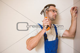 Handyman hammering nail in wall