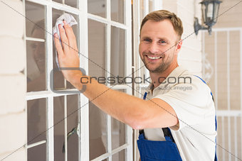 Handyman cleaning the window and smiling