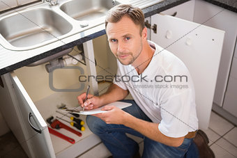 Plumber crouching and taking notes