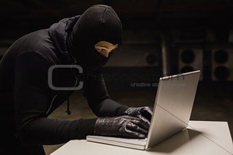 Robber at desk hacking a laptop
