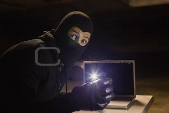 Robber looking at camera while making light with his phone
