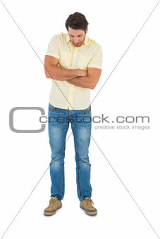 Handsome man standing looking down with arm crossed