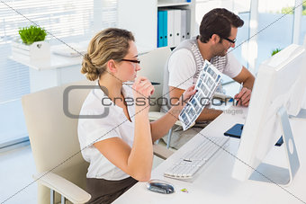 Blonde editor looking over contact sheet at her desk
