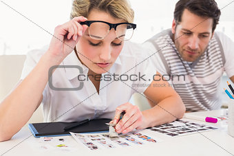 Editor using magnifying loupe to view the contact sheet