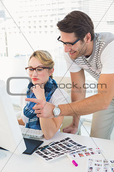 Cheerful photo editor pointing at a computer