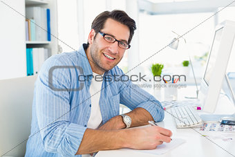 Photo editor writing on a paper while looking at camera