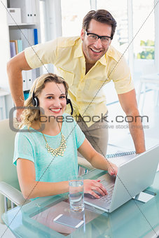 Portrait of a woman wearing headphone and her colleague