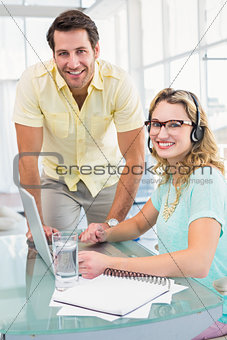 Portrait of a woman wearing headphone and her colleague