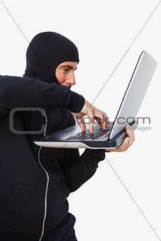 Burglar with balaclava hacking a laptop