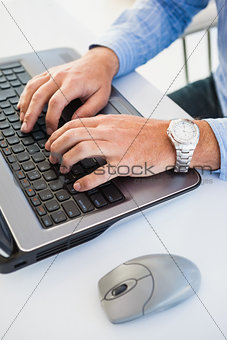 Close up of hands with wrist watch typing on laptop