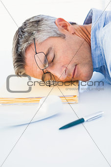 Man with glasses sleeping on his files