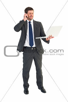 Businessman talking on phone holding laptop
