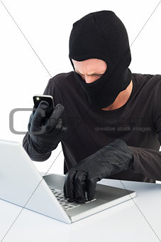 Hacker using laptop and phone