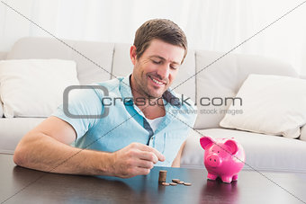 A man putting coins in piggy bank