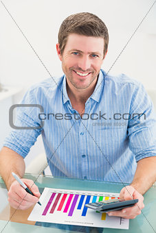 Smiling businessman working on measuring graph at his desk