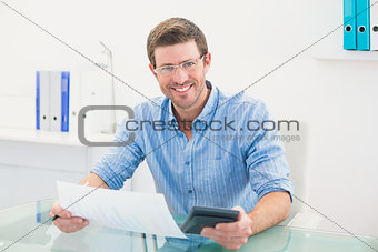 Smiling businessman working on his finances at his desk