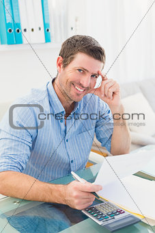 Smiling businessman working on his finances at his desk