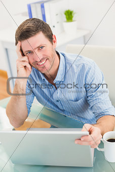 Smiling businessman using his laptop at desk
