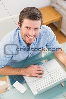 Smiling businessman using his laptop at desk