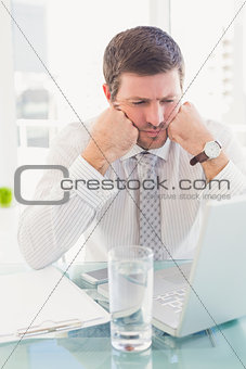 A businessman looking at laptop at desk