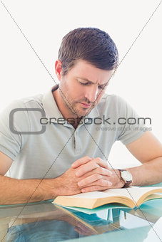 Casual businessman sitting at desk reading a book