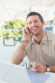 Smiling businessman making a call at his desk