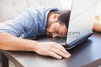 Man sleeping with head resting on laptop keyboard
